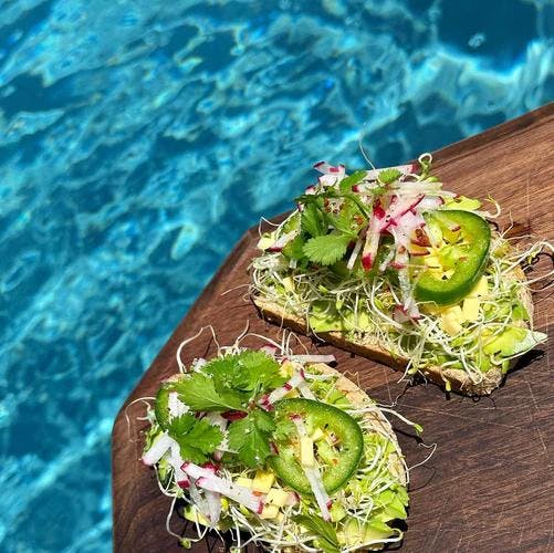 Two slices of grain free bread with mashed avocado, alfalfa sprouts, jalapeño, and radish with a dash of JF Spicy Salt. 