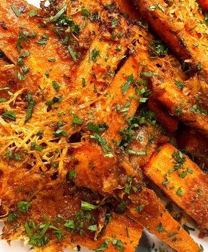 Roasted carrots covered in melted vegan parmesan cheese 