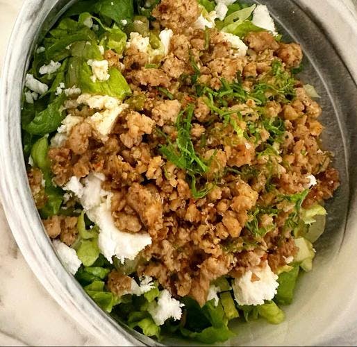 Green salad topped with ground turkey and garnished with fresh dill. 