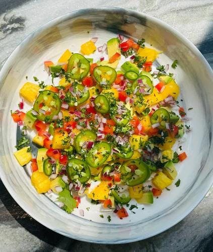 Vegan coconut yogurt bowl topped with diced pineapple, avocado, red onion, red pepper, cilantro, jalapeño, a drizzle of olive oil and a sprinkle of JF Spicy Salt.