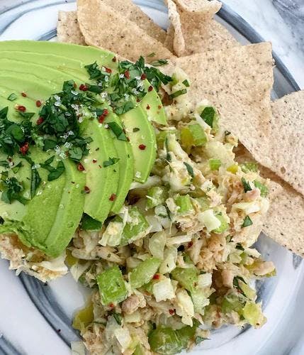 Quick and easy tuna salad plated with grain free chips and sliced avocado