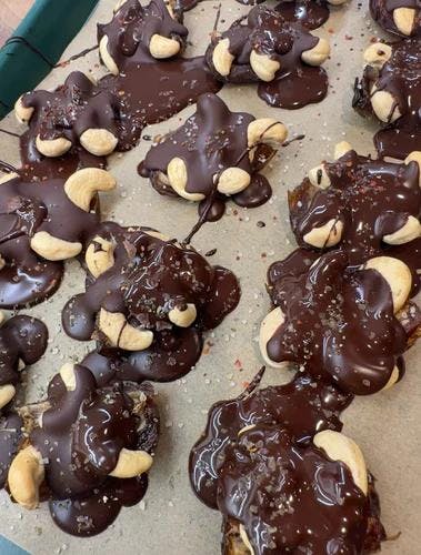 Halved dates and cashews covered in melted dark chocolate 