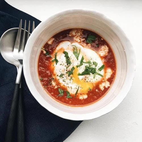 Bowl of fresh tomato sauce served with a poached egg. 