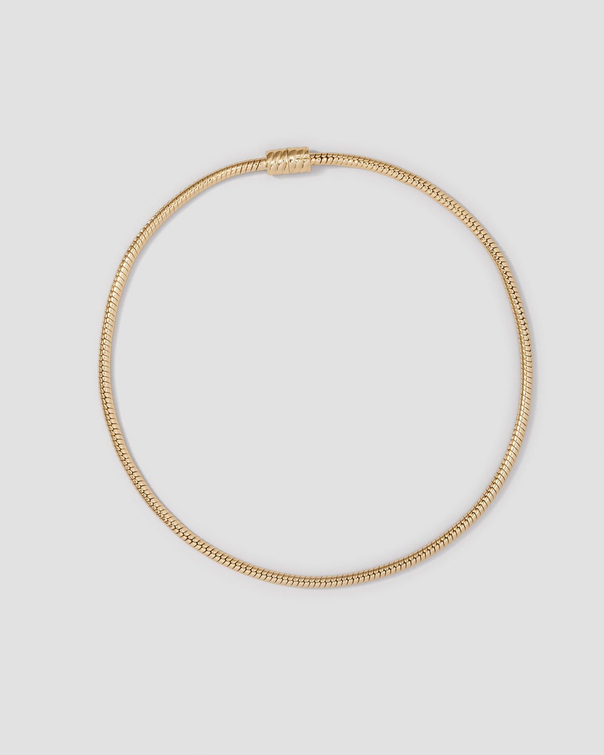 Gold necklace on a light gray background